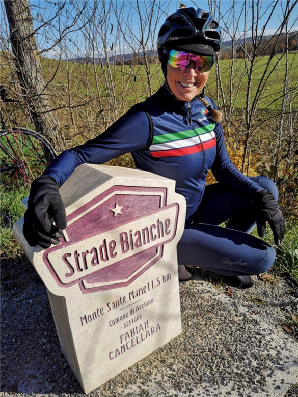 Calla Barras poses next to one of the iconic Strade Bianche climb markers of the Monte Sante Marie, fastets time set by Fabian Cancellara